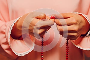 Concentrated woman praying wearing rosary beads. Namaste. Close up hands.