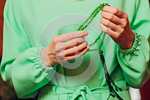 Concentrated woman praying wearing rosary beads. Namaste. Close up hands.