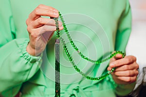 Concentrated woman praying wearing rosary beads. Namaste. Close up hands.