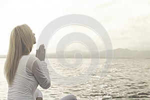 Woman prays meditating in front of a ocean view photo