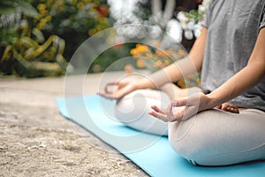 Concentrated woman sitting in lotus position yoga at summer garden park plants and blossom flowers