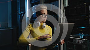 Concentrated woman IT specialist working on laptop in server room