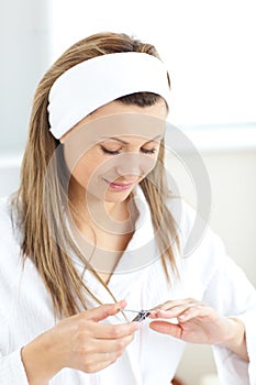 Concentrated woman using a nail scissors