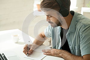 Concentrated worker in headphones watching webinar noting import