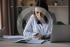 Concentrated young 20s female student reading textbook.