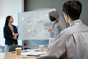 A concentrated young Asian businessman is listening carefully to a presentation in a meeting