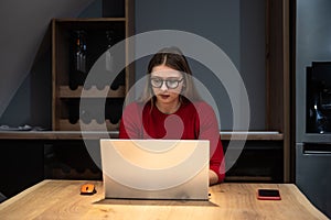 Concentrated young beautiful businesswoman working on laptop in modern home office. Expert female finishing her job for internet
