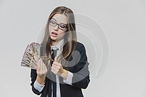 Concentrated young business woman is counting a pile of money, isolated on white background. Girl is satisfied by huge