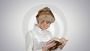 Concentrated young business woman holding and reading book on white background