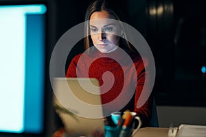 Concentrated young business woman working with laptop in the office at night
