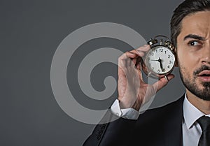 Concentrated young businessman with alarm clock