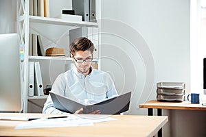 Concentrated young businessman working with documents in folder