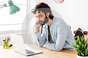 Concentrated young businessman working on laptop computer at home office