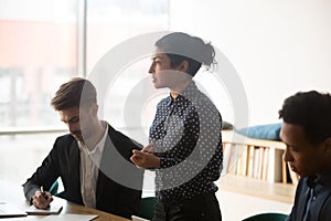 Concentrated young female employee with diverse team at office