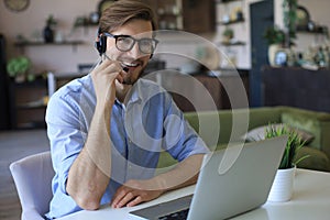 Concentrated young freelancer businessman using laptop for video conferance, working remotely online at home