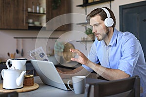 Concentrated young freelancer businessman using laptop for video conferance, working remotely online at home