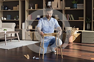 Concentrated young male homeowner fixing broken wooden furniture.