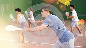 Concentrated young man paleta fronton player hitting ball with racket