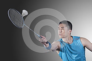 Concentrated Young man playing badminton, hitting
