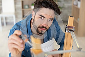 concentrated young man reading instructions to assemble furniture