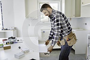 Concentrated young man work with white cabinet in the kitchen