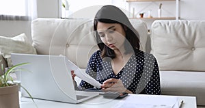 Concentrated young mixed race asian woman paying bills online.