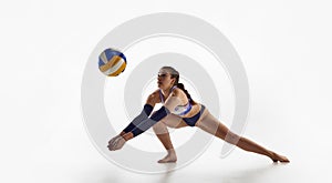 Concentrated young woman, beach volleyball player in motion, training, hitting ball over white studio background.