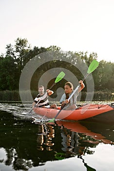 Concentrated young woman and her boyfriend kayaking together in a lake on a late summer afternoon