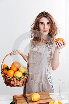 Concentrated young woman holding basket with a lot of citruses
