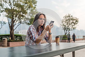 Concentrated young woman typing a text message on her mobile phone outdoors. Serious female using smartphone.