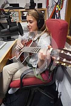 Concentrating pretty singer recording and playing guitar