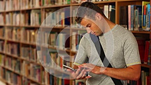 Concentrating student using his tablet standing in the library