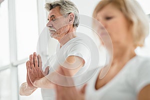 Concentration and calm. Sporty senior couple doing breathing exercise in yoga class.Health concept