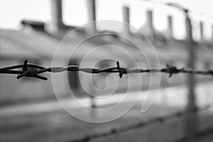 Concentration camp Auschwitz, Oswiecim, monochrome. Barbed wire fence with barrack on background. Holocaust memorial