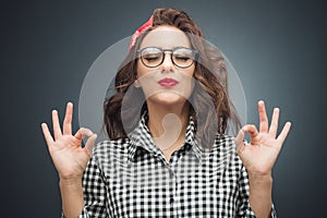 Concentration and enjoying. Young woman with closed eyes shows excellent sign with finger while enjoying over dark gray - black