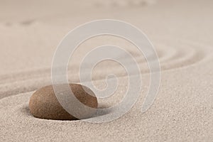 Concentration trough focus on a zen meditation stone. Round rock in sand texture background