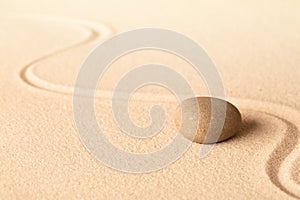 Concentration trough focus on a zen meditation stone. Round rock in sand texture background