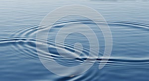 Gentle ripples create abstract patterns on a calm blue water surface