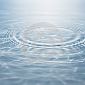 Concentric ripples spread across a surface of clear water, creating a pattern of waves.