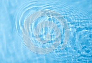 Concentric waves on blue water surface after falling drops, top