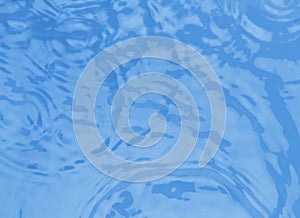 Concentric waves on blue water  after falling drops, top view