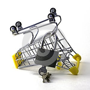 the concept of abandoning the purchase of reasonable consumption is an inverted shopping cart with a padlock on a white