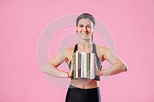The concept of active, healthy lifestyle. Woman fitness trainer dressed in black sportswear holding several books in the hands.