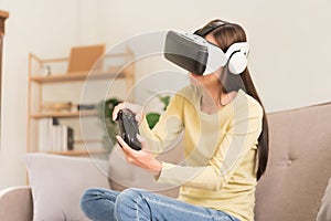 Concept of activity in home, Young woman having fun while playing game with VR glasses and joystick