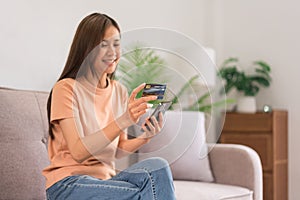 Concept of activity in home, Young woman using phone and credit card to payment for shopping online