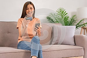 Concept of activity in home, Young woman using phone and credit card to payment for shopping online