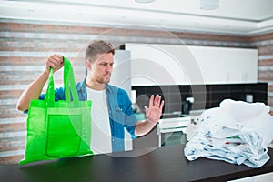 Concept against unreasonable use of plastic bags. Use a reusable bag - save nature from microplastics. Young man chooses