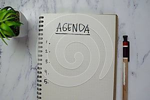 Concept of Agenda write on a book isolated on Wooden Table