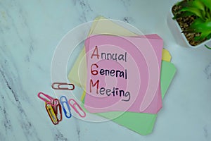 Concept of AGM - Annual General Meeting write on sticky notes isolated on Wooden Table