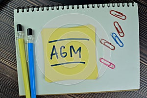 Concept of AGM - Annual General Meeting write on sticky notes isolated on Wooden Table
